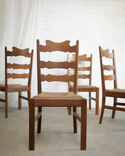 Load image into Gallery viewer, Four wooden ladder-back dining chairs with woven cane seats arranged in a room with a white brick wall and light concrete floor.