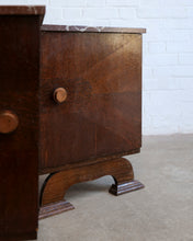 Load image into Gallery viewer, A close-up of a dark brown wooden nightstand or cabinet with a single drawer, featuring a round wooden knob and decorative curved legs, set against a white brick wall and concrete floor.
