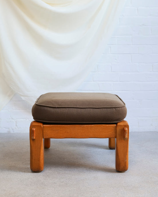 Oak framed footstool with a sprung base and brown cotton mix cushion
